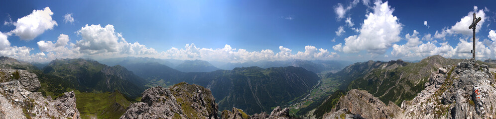 Panoramic view of Klostertal valley and Verwall mountain group seen from Roggelskopf peak with its summit cross in the Vorarlberg Alps, Austria