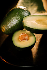 Fresh avocado halves with pit on a dark background showcasing vibrant green flesh and textured skin