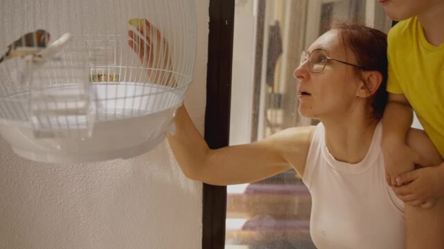Mother and son caring for zebra finches in a cage