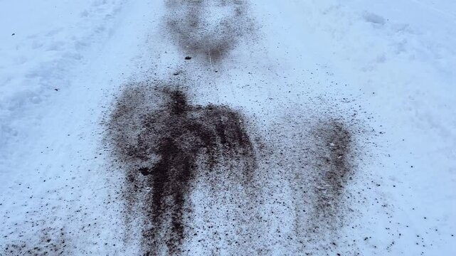 The road in a winter park or forest is sprinkled with sand and salt, reagents for roads. Winter, ice