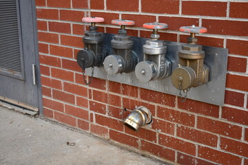 Pump test connection on large hospital. Four water pipe connections with large valve handles.