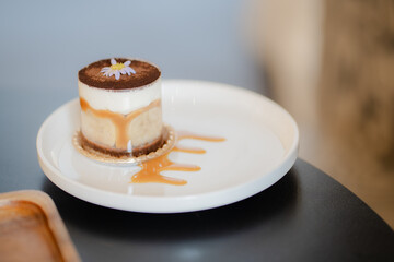 A cup of Banoffee with mini spoon on a wood dish in copy space concept.