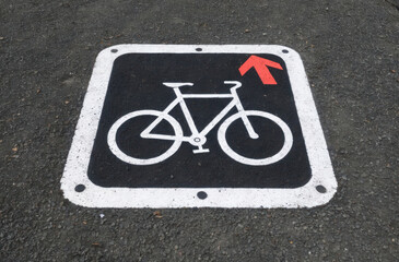 Naklejka premium Bike path sign on asphalt: Painted symbol, road marking, cycle lane. Guidance for cyclists and traffic.