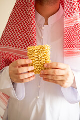 Obraz premium Saudi in Arab dress holding out instant noodles