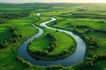 Winding river flowing through lush green fields at sunset