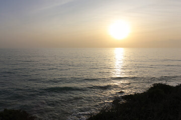 Bright sun setting on calm ocean creating golden reflection on water surface