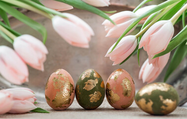 The concept of a bright Easter holiday. Delicate Easter eggs in pink, gold and green tones and delicate pink tulip flowers.