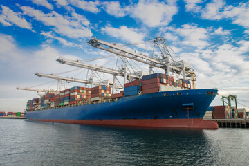 Container ship unloading at port by cranes.	