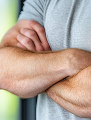 Fototapeta premium Close-up of crossed arms in casual t-shirt