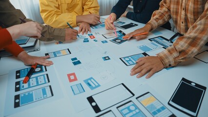 A vibrant design session showing diverse hands engaged in creating user interface prototypes. The table displays sketches, digital devices, and collaborative tools fostering creativity. SACTR