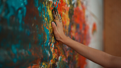 Side view of highschool girl hand placed at colorful stained wall and remove the hand. Closeup of room was pained or decorated with hand print in art lesson. Creative activity concept. Edification. © InfiniteFlow
