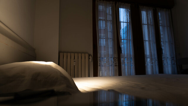 bedroom of a house at sunset with the bed made and a window at the back