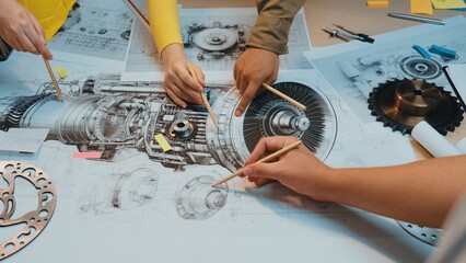 A group of professionals collaborates on a detailed engineering blueprint in a modern workspace, using pencils to highlight critical design elements and showcase teamwork. SACTR