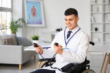 Young male doctor in wheelchair with sphygmomanometer at hospital