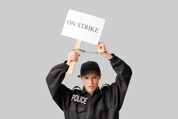 Protesting female police officer in handcuffs holding placard with text ON STRIKE against grey...