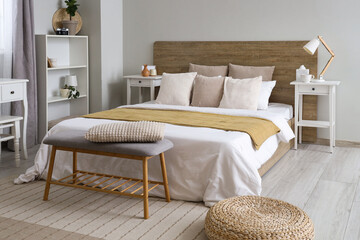 Interior of light modern bedroom with big bed, shelving units and bedside table