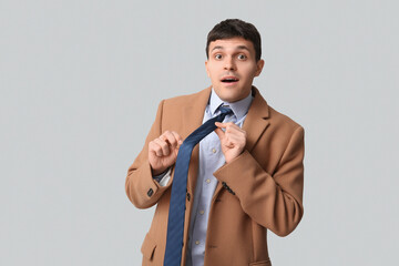 Surprised young man straightening his tie on white background