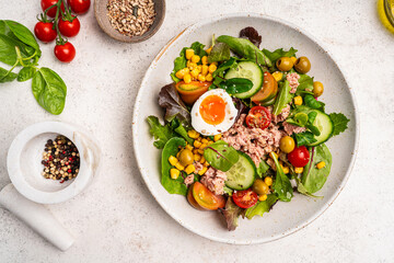 Tuna salad with tomatoes, cucumber, corn, olives , eggs and onion on white stone background, top view. High quality photo