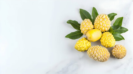 Yellow Spiky Fruits Arranged With Green Leaves On White Marble Surface