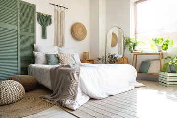 Stylish interior of light bedroom with poufs near comfortable bed