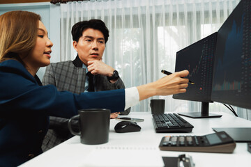 Asian business partners pointing to profit highest dynamic stock exchange data on computer screen value rate online website program. Investor showing financial on real time at modern office. Infobahn.