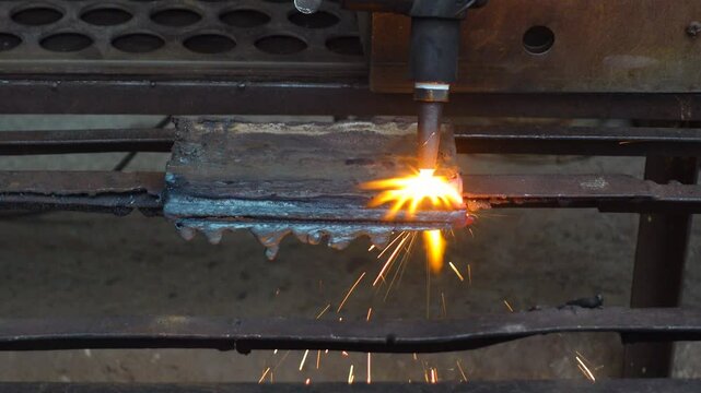 A piece of iron is being cut in half with a gas-cutting machine. Oxy-fuel welding and cutting machine.