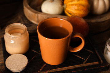 Autumn composition with cup of green tea, candle and tray on wooden background, closeup