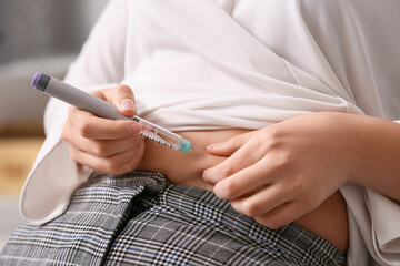 Diabetic woman giving herself insulin injection in office, closeup