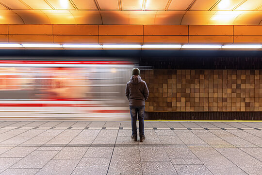 A young boy standing on a subway platform as the train speeds past, capturing the urban energy, public transport experience, and the anticipation of travel in a bustling city setting.