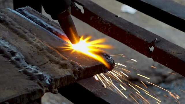 A piece of iron is being cut in half with a gas-cutting machine. Oxy-fuel welding and cutting machine.