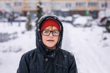 Portrait of a boy in glasses warmly dressed on a cold snowy day