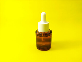 small glass bottle with rubber dropper cap on yellow