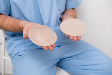 doctor holding breast enlargement implant in hands, plastic surgery concept, beauty enhancement,...