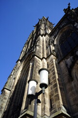 Die evangelisch Apostelkirche mit Kirchturm und Straßenlaterne vor blauem Himmel im Sonnenschein...