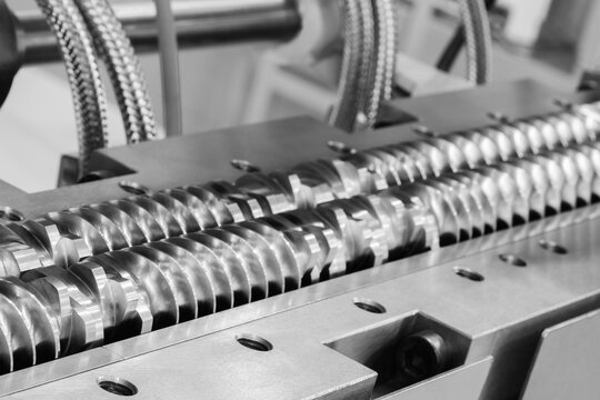 Spiral screw shaft for feeding granules into production machine for manufacture products from pvc plastic extrusion technology industrial concept background