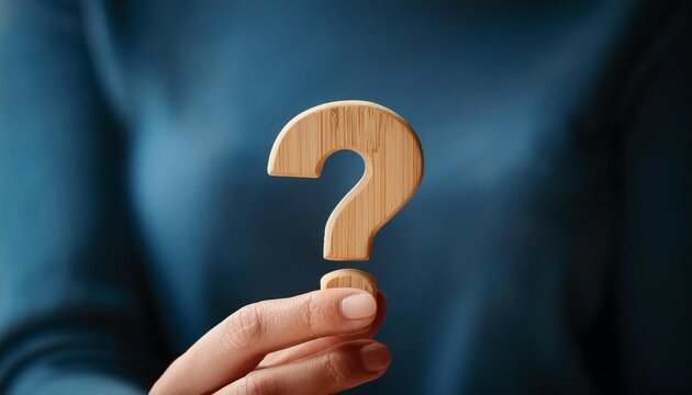 wooden question mark held by a hand symbolizing inquiry and curiosity