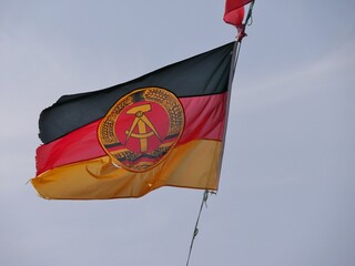 DDR-Flagge weht vor Himmel