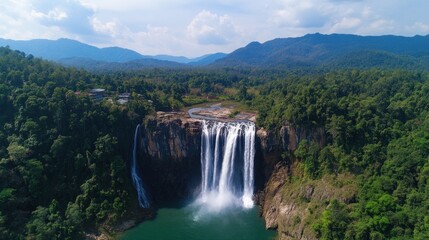 Obraz premium Majestic waterfall cascading into a tranquil pool, surrounded by lush green rainforest and mountains