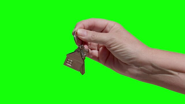 Woman Holds Out New House Keys and House Shaped Keychain Against Green Screen.