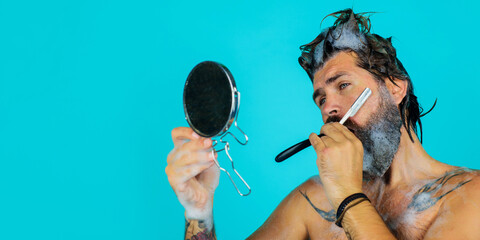 Handsome man with beard and mustache shaves with vintage razor. Beard care. Bearded man shaving...