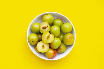 Fresh green plum fruit on yellow background.