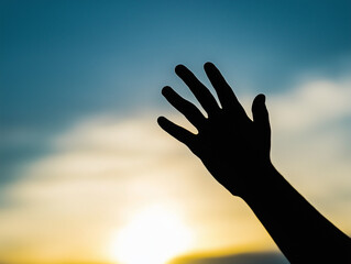 Silhouette of a Raised Hand Against a Golden Sunset
