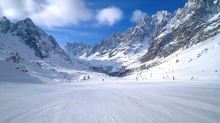 Snow covered mountain landscape. Snowy mountains rise under a bright blue sky with fluffy white clouds. Ski slope is ready for skiing.