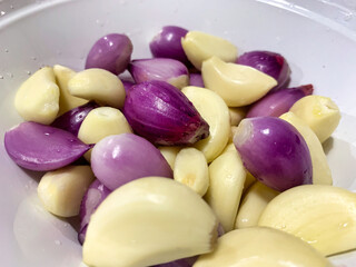Garlic and fresh shallots are mixed and placed in a white bowl.