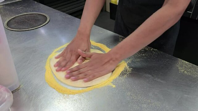 Chef's hands kneading dough on the cooking table, cooking pizza