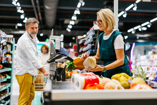 Cashier scanning groceries at checkout counter in supermarket