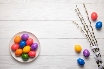 Easter composition colored Easter eggs and willow branches lie on a white wooden table top view