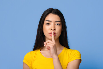 Shhh. Mysterious young asian lady showing keep silence sign at camera, beautiful korean female...