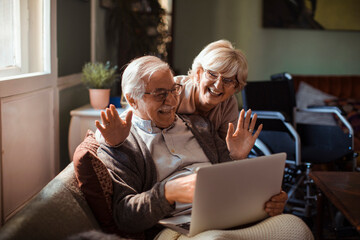 Elderly couple embracing while using laptop at home