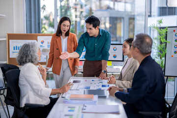 A group of people are gathered around a table with a lot of papers and graphs